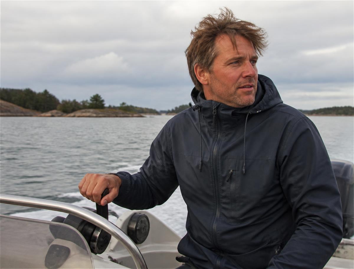 En skeppare vid rodret på en motorbåt i skärgården